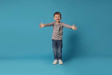 Mutlu küçük çocuk açık mavi arka planda dans ediyor