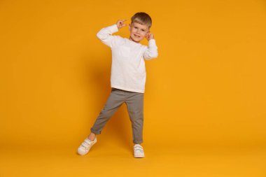 Mutlu küçük çocuk turuncu arka planda dans ediyor