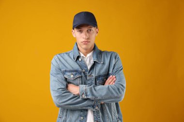 Turuncu arka planda şık beyzbol şapkalı genç adam.