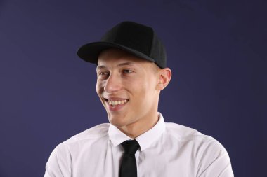 Koyu mavi arka planda şık beysbol şapkalı genç adam.