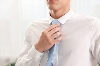 Evde şık kravat bağlayan adam, yakın plan.