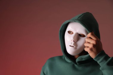 Anonimlik. Kırmızı arkaplanda maske takan adam, metin için boşluk