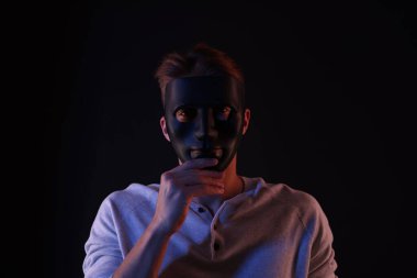 Anonimlik. Siyah arka planda maskeli bir adam