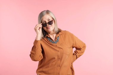 Pembe arka planda şık giyinmiş son sınıf öğrencisi bir kadın.