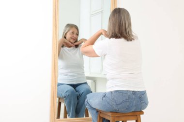 Güzel son sınıf öğrencisi kadın aynada kendine bakıyor.