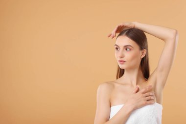 Bej arkaplandaki epilasyondan sonra pürüzsüz cilt gösteren genç kadın, metin için boşluk