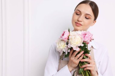 Beyaz duvarın yanında güzel şakayık demeti olan bir çiçekçi.