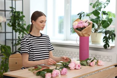 Çiçekçinin ahşap masasında şakayık buketi yapan bir çiçekçi.