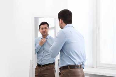 Yakışıklı adam aynada kendine bakıyor.