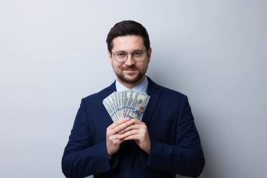 Gri arka planda dolar banknotları olan açgözlü bankacı.