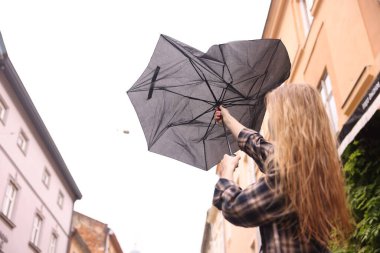 Açık havada şemsiyesi kırık bir kadın, düşük açılı.