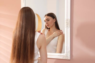 Güzel bir kadın aynada kendine bakıyor.