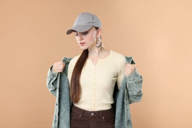 Beyzbol şapkalı güzel bir kadın bej arka planda.