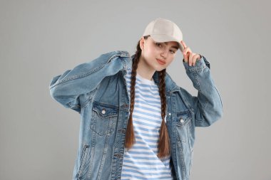 Gri arka planda şık beyzbol şapkalı güzel bir kadın.