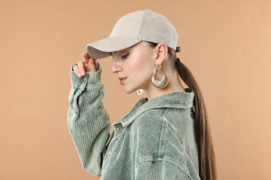 Beyzbol şapkalı güzel bir kadın bej arka planda.