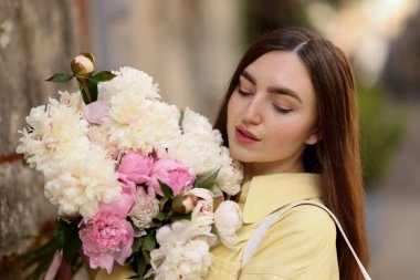Şehir caddesinde elinde şakayık demeti olan bir kadın