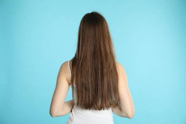 Uzun saçlı, açık mavi arka planda bir kadın.