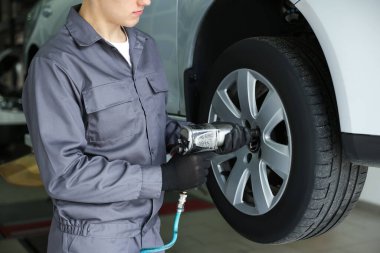 Tamirci araba servisinde lastik değiştiriyor, yakın plan.