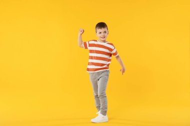 Mutlu küçük çocuk turuncu arka planda dans ediyor