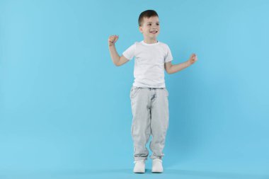 Açık mavi arka planda dans eden mutlu küçük çocuk. Metin için boşluk