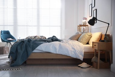 Yumuşak çarşaflı rahat bir yatak, şık bir odada komodin ve lamba. Ev tekstili