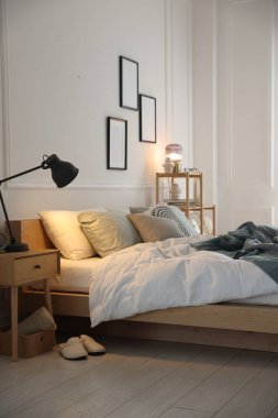 Yumuşak çarşaflı rahat bir yatak, şık bir odada komodin ve lamba. Ev tekstili