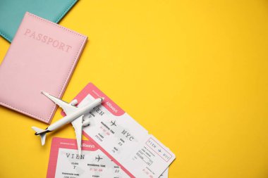 Biletli pasaportlar ve sarı arka planda uçak modeli, düz konum. Metin için boşluk