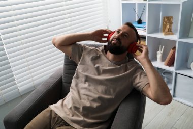 Uyum. Evde kulaklıkla müzik dinleyen bir adam.