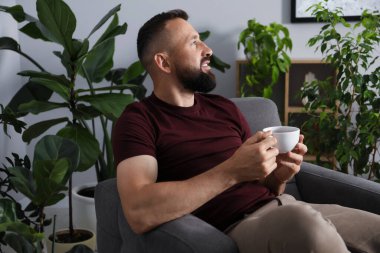 Uyum. Evdeki koltukta içki içen adam.