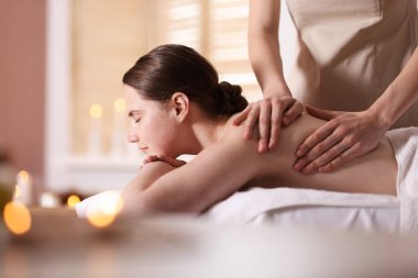 Kadın masaj yaptırıyor, masaj salonu yağlı, mesaj için yer var.