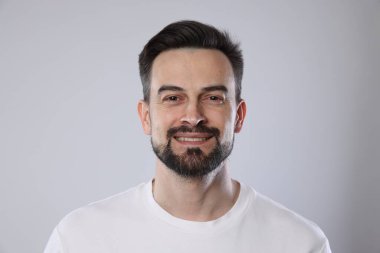 Gri arka planda gülümseyen adamın portresi, yakın plan.