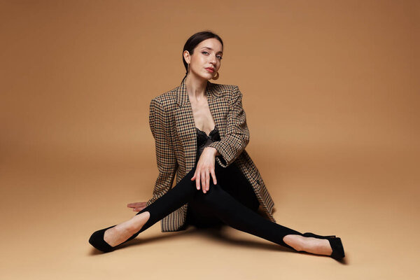 Полнометражный портрет красивой женщины в стильном наряде на бежевом фоне