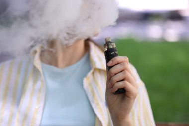 Dışarıda elektronik sigara içen genç bir kadın, yakın plan.