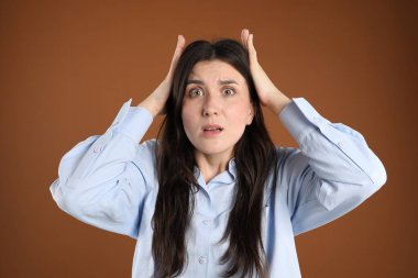 Kahverengi arka planda şok olmuş kadın portresi