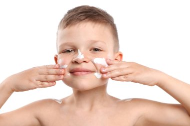 Küçük çocuk beyaz arka planda cildine güneş kremi sürüyor.