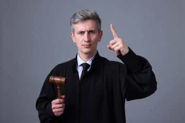 Gri arka planda parmak sallayan çekiçli yargıç