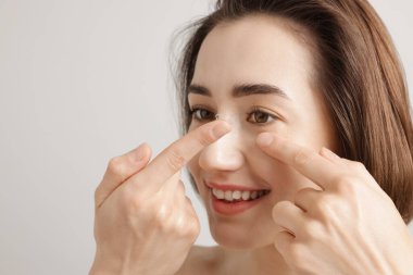 Kadın arka plana kontak lens takıyor, yakın plan.