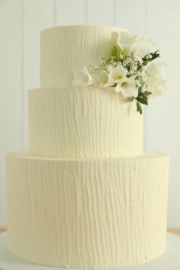 Bulanık arkaplanda çiçek dekoru olan lezzetli düğün pastası, yakın plan.