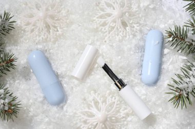 Nemlendirici dudak kremleri, Noel dekorasyonu ve yapay kar üzerindeki köknar ağacı dalları. Kış bakımı