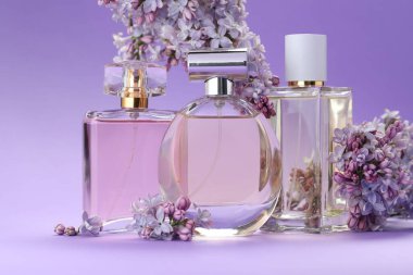 Parfümlü şişeler ve mor arkaplanda leylak çiçekleri, yakın plan.
