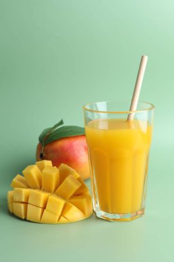 Bardakta lezzetli mango suyu ve yeşil arka planda taze meyve.
