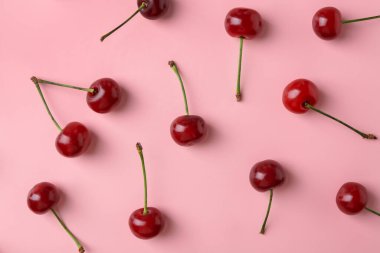 Pembe arka planda taze kirazlar, düz uzanmış.