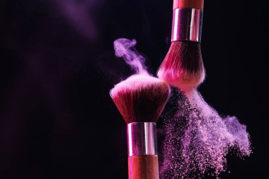 Renkli göz gölgeli makyaj fırçaları siyah arka planda neon ışıkları, yakın plan