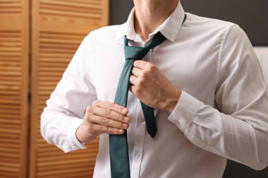 Evde şık kravat bağlayan adam, yakın plan.