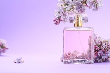 Parfüm şişesi ve mor arkaplanda leylak çiçekleri, yakın plan. Metin için boşluk