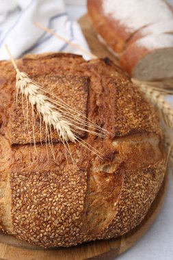 Taze pişmiş ekmek, susam tohumları ve açık gri masada çiviler, yakın plan.