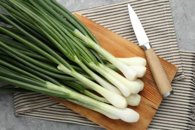 Taze taze taze soğanlar kesme tahtası ve bıçakla gri masada, düz yatıyordu.