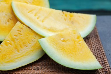 Yüzme havuzunun yanındaki masada olgun sarı karpuz parçaları, yakın plan.