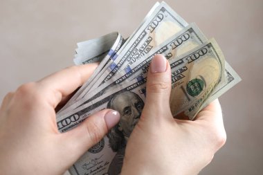 Bej arka planda dolar sayan bir kadın, yakın plan.