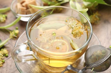 Taze ıhlamur çayı, şeker küpleri ve çiçekler ahşap masada, yakın plan.